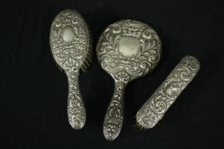 A silver repousse dressing set with foliate and floral design. A mirror and two brushes. Hallmarked: