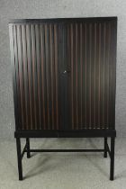 A contemporary ebonized cabinet on stand. H.169 W.102 D.60cm.