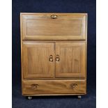 An Ercol elm side cabinet with fall front. H.110 W.83 D.45.cm