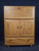 An Ercol elm side cabinet with fall front. H.110 W.83 D.45.cm