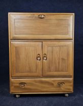 An Ercol elm side cabinet with fall front. H.110 W.83 D.45.cm