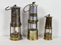 Three miner's lamps, including a Thomas and Williams, J H Naylor of Wigan, and another. Largest is