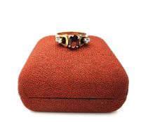 A boxed 1970's 9ct yellow gold sculptural design garnet and diamond dress ring, set to centre with