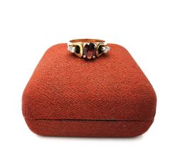 A boxed 1970's 9ct yellow gold sculptural design garnet and diamond dress ring, set to centre with