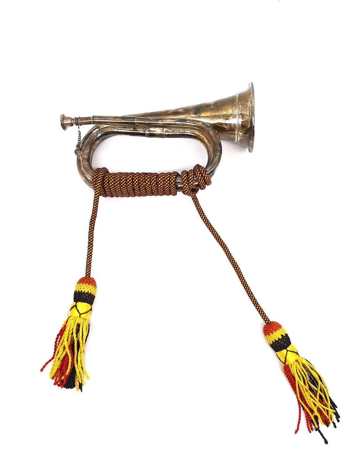A silver plated bugle with red black and yellow silk rope with tassel ends. L.28 W.19cm