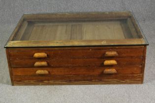 A 1920's pine planners chest, with later glass top to form a coffee table. H.40 W.123 D.92cm.
