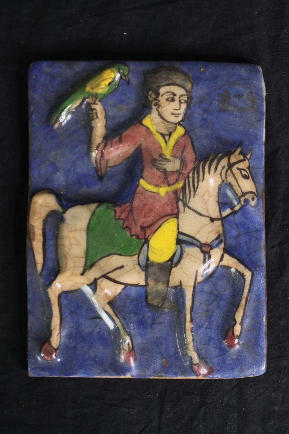 A Persian Qajar pottery tile, depicting a figure on horseback. H.19 W.14cm. - Image 2 of 3