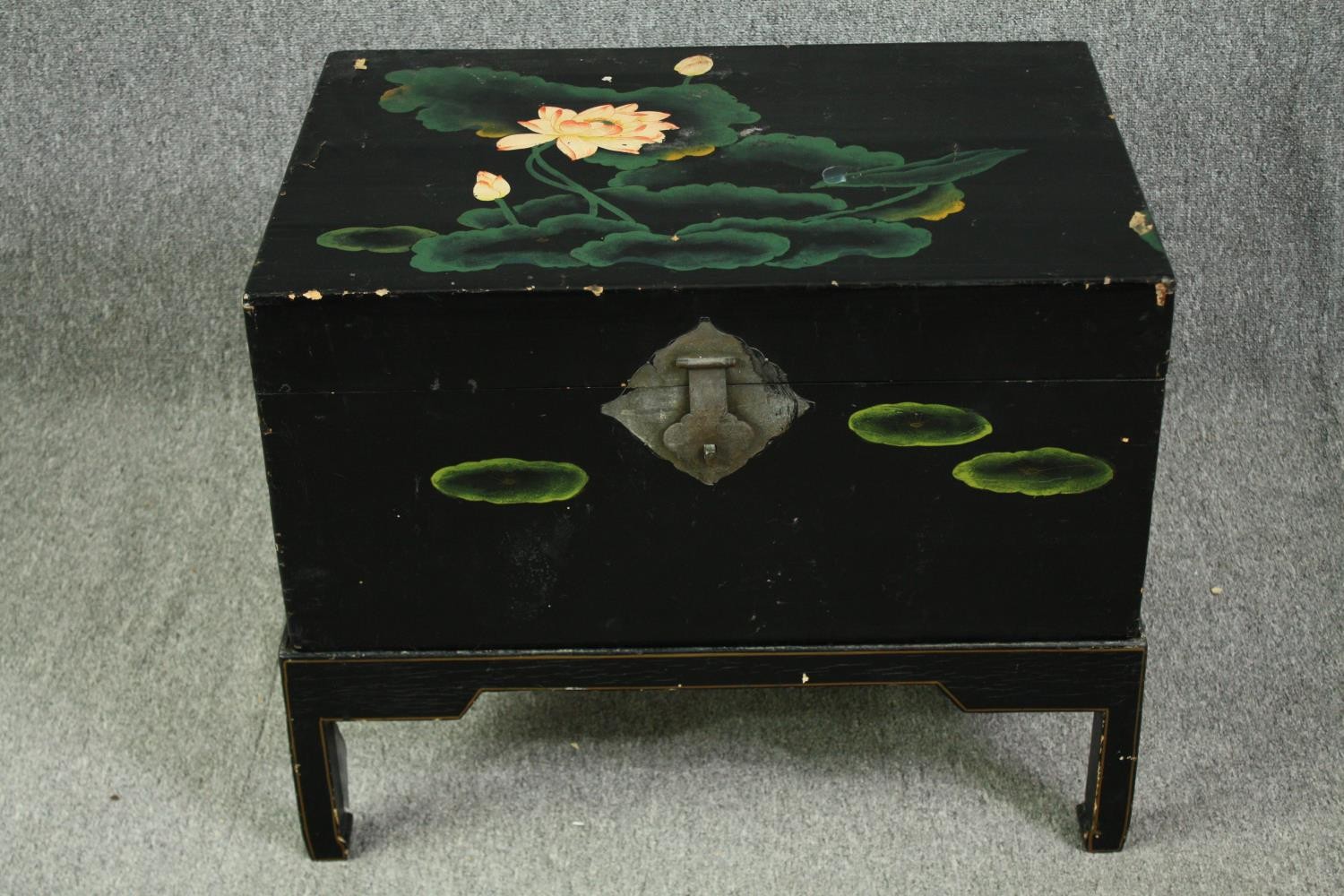 A Chinese black lacquered travelling chest on stand, hand decorated with peonies, early 20th