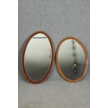 Two oval mirrors, one in oak, the other walnut, with bevelled glass H.95 W.55cm.