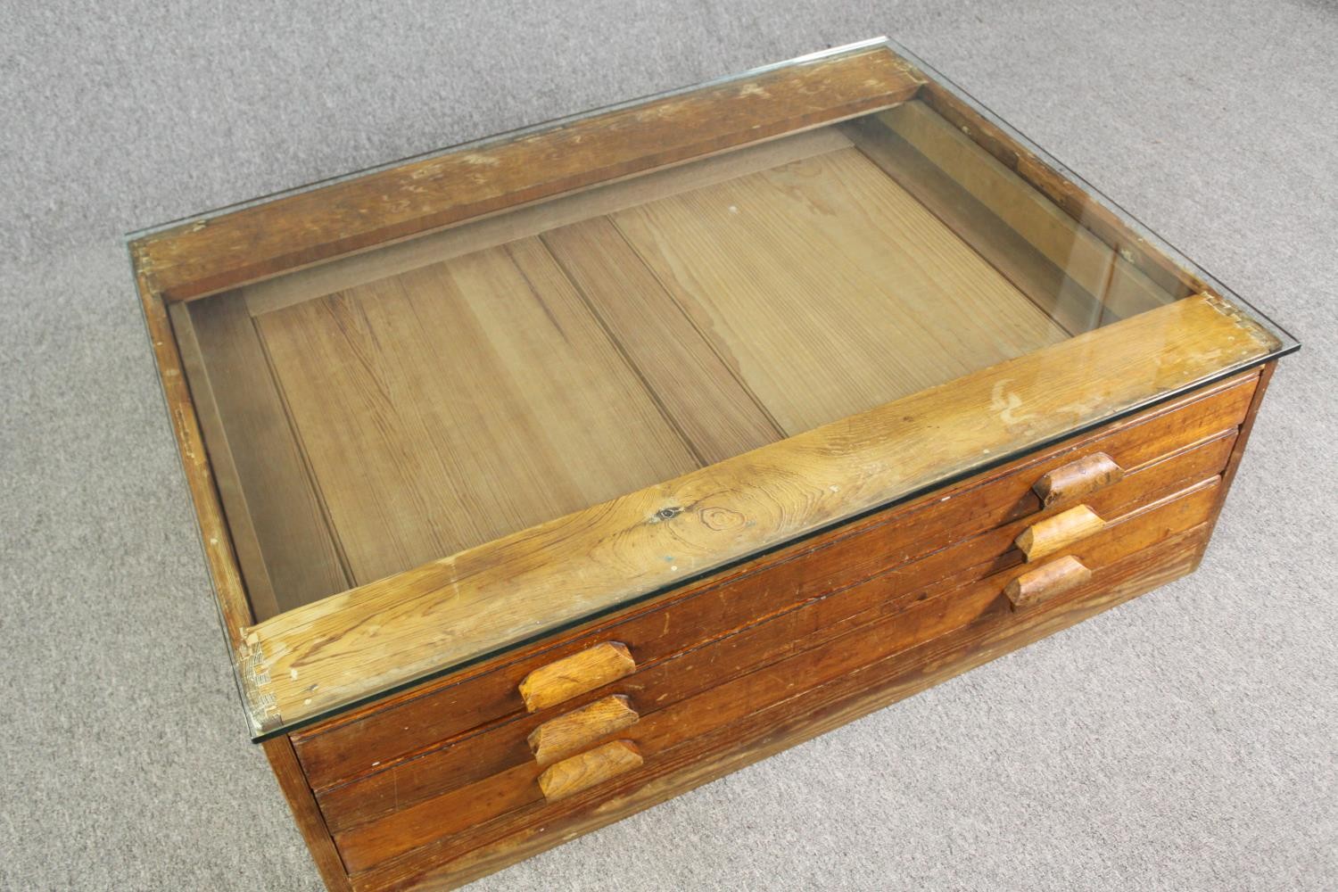 A 1920's pine planners chest, with later glass top to form a coffee table. H.40 W.123 D.92cm. - Image 4 of 8
