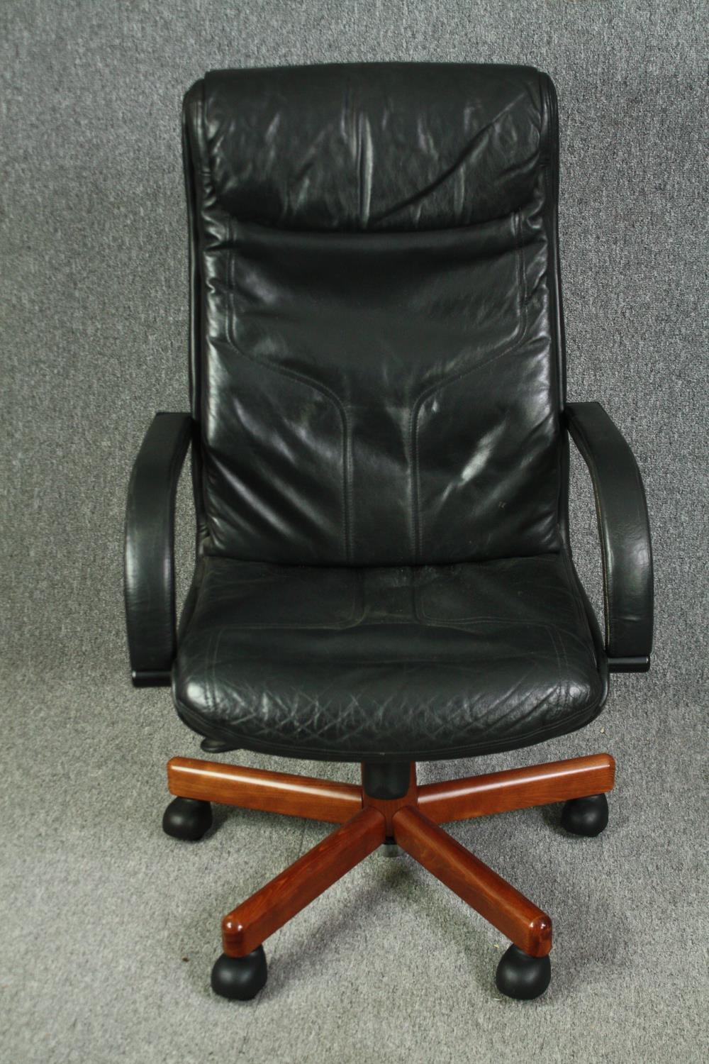A 1970's style office swivel chair, with black leather upholstery.