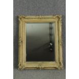 A cream painted carved wood and gesso wall mirror. H.96 W.77cm.