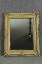 A cream painted carved wood and gesso wall mirror. H.96 W.77cm.