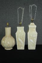 A group of three celadon glazed table lamps with raised decoration of birds and butterflies, in