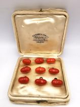 A collection of nine 19th century torpedo shaped orange coral and yellow metal (tested 9ct gold)