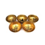 A set of five early 20th century Japanese gilt lacquered and hand painted bowls, each with a