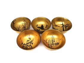 A set of five early 20th century Japanese gilt lacquered and hand painted bowls, each with a