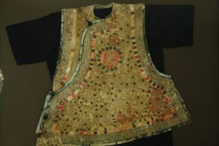 † A framed and glazed 19th century Oriental child's tunic with mirror decoration and floral