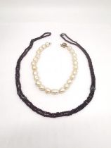 Two necklaces, a faux pearl necklace with floral clasp along with a garnet faceted bead long