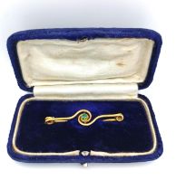 A velvet cased French early 20th century 18ct yellow gold emerald set spiral bar brooch, set to