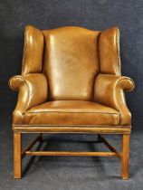 A George III style oak wingback armchair, with studded tan leather upholstery, 20th century.