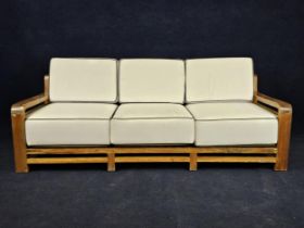 An Art Deco style teak garden or conservatory sofa, with piped white upholstery. H.96 W.230 D.95cm.