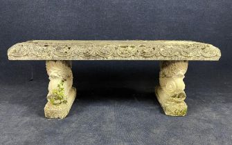 A weathered composition stone three section garden bench on dolphin supports. H.50 W.130 D.42cm.