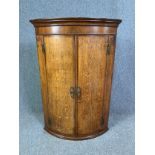 A Georgian oak bow fronted corner cupboard. H.108 W.74 D.51cm