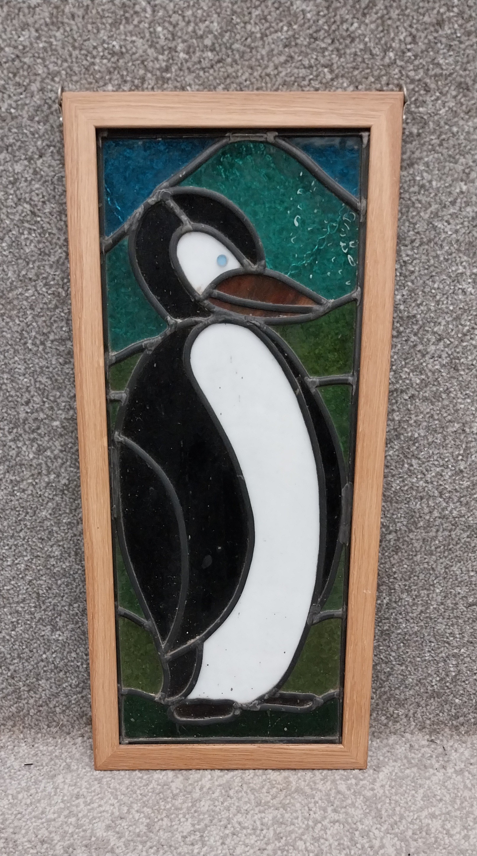 A mid 20th century Art Deco style leaded stained glass penguin panel, in an ash frame. H.52 W.23.