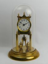 Brass anniversary clock with an enamel dial and glass dome, 30cm.