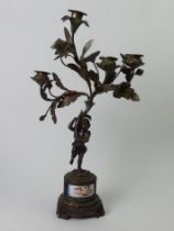 19th century bronze figural candelabrum with an inset porcelain panel. 46cm high. UK Postage £20.