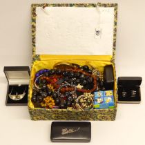 A box of costume jewellery including an amber bead necklace and a silver and gold necklace.