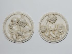 A pair of reconstituted marble wall plaques depicting classical scenes in relief, one signed to