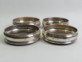 A set of four Elizabeth II silver and mahogany wine/champagne bottle coasters, London 1990 & 1991.
