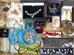 A box of costume jewellery including marcasite brooches and loose garnets.