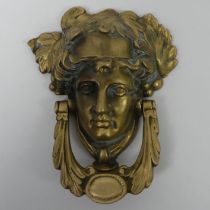 Ornate brass door knocker in the form of a classical head, 19cm x 15cm.