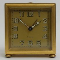 A gilt metal travel alarm clock with a Swiss eight day movement. 5.8 x 6.6 cm.