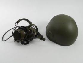 A vintage British Army combat helmet together with a set of head crew radio headphones.