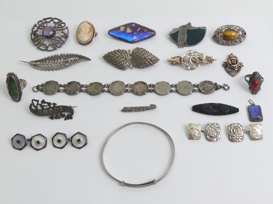 A box of silver jewellery including brooches and enamel cufflinks.