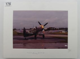 A mounted photograph of a burning Spitfire signed by Flight Lieutenant Rodney Scrase. 39 x 30 cm.