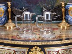 A PAIR OF 19TH CENTURY STERLING SILVER AND GLASS CLARET JUGS SURMOUNTED BY LIONS