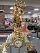 A GILT FIGURAL DECORATIVE MANTLE CLOCK WITH VARIEGATED ONYX BASED , THE FIGURAL SURMOUNT WITH LAMP