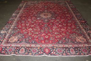 A LARGE EASTERN WOOLLEN RUG IN MAINLY RED AND BLACK PATTERN 377 X 275 CM