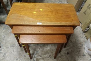 A VINTAGE TEAK NEST OF THREE TABLES - WATER DAMAGED