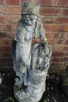 A CONCRETE WATER FEATURE OF A LADY FILLING A WATER JUG