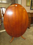 A MAHOGANY TILT TOP OVAL TABLE ON CARVED BASE