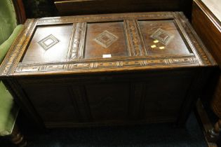 A CARVED OAK PANELLED COFFER -0 W 101 CM