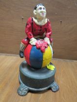 A CAST METAL NOVELTY MONEY BANK IN THE FORM OF A CLOWN ON A BALL