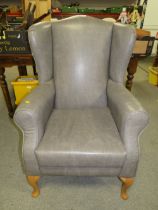 AN UPHOLSTERED WING ARMCHAIR A/F