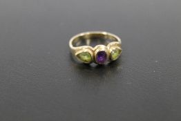 A HALLMARKED 9 CARAT GOLD AMETHYST AND PERIDOT THREE STONE RING IN RUB OVER SETTING approx weight